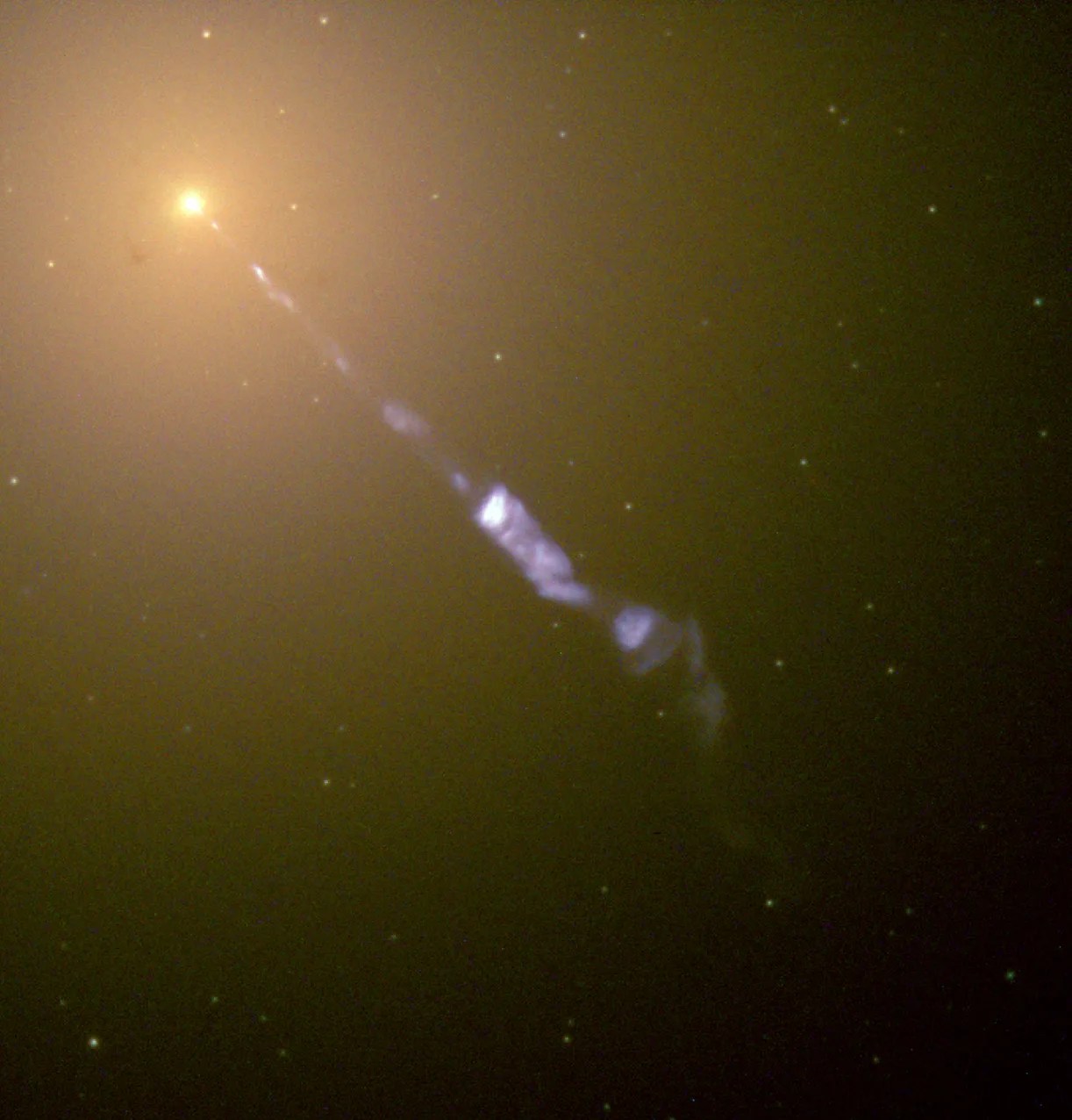 Hubble Space Telescope image of the M87 galaxy’s core, showing a bright galactic nucleus with a narrow blue jet of plasma extending diagonally across the frame